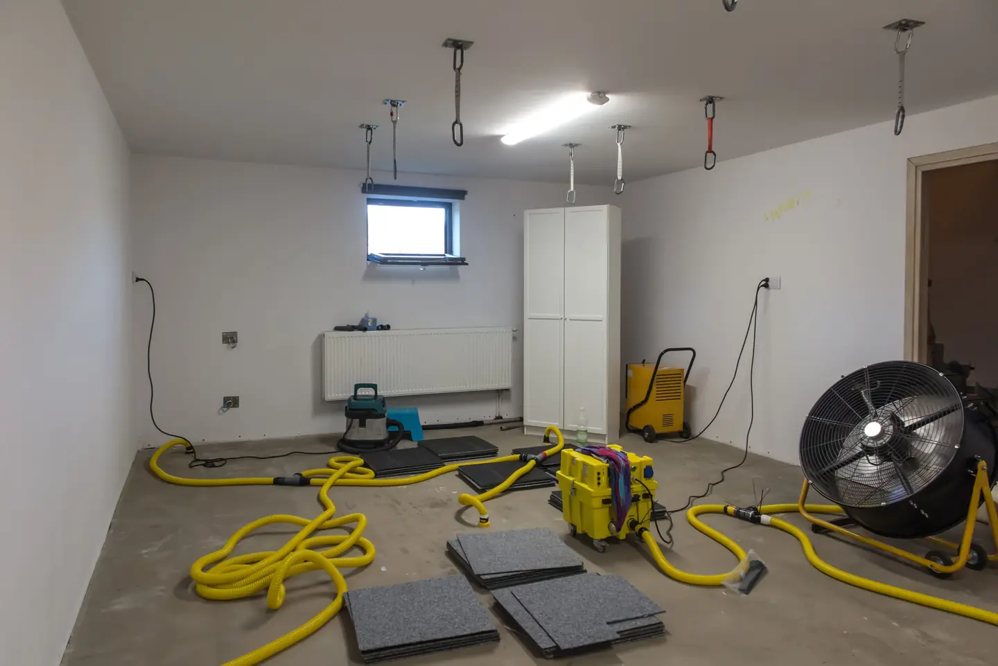 Air movers and a dehumidifier drying an emptied room after water damage