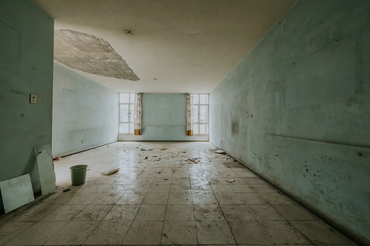 A ceiling caved in after water soaked through it, with debris across the floor below